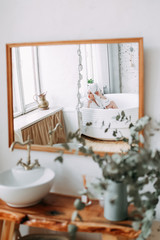 Morning of the bride. Happy beautiful with a snow-white smile and red lips girl in a white robe and with a towel on her head sitting laughing and having fun in the bath on a white background, relax