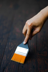 Hand man holding yellow-brown paintbrush for paint on creative acrylic color on plate by hand drawn painting. Colorful splashing in the drawing board.It's wet texture background for wallpaper.