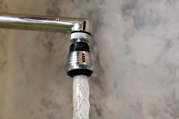 Aerator nozzle on faucet mixer with rotating head. A close-up photograph of a frozen moment flowing from a tap water.