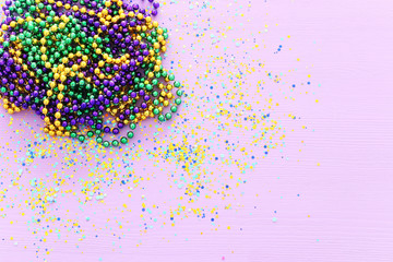 Multi colored mardi gras beads, blue, green, yellow, pink, purple and gold over purple background © tomertu