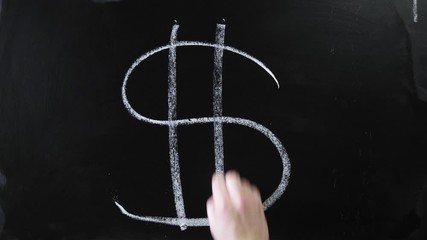 Dollar symbol. The sign is written on a chalk board. Male hand draws in chalk on a blackboard