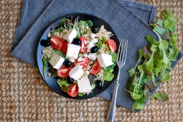 Fresh salad with lettuce, black olive, tomato, arugula, cous-cous and camembert cheese