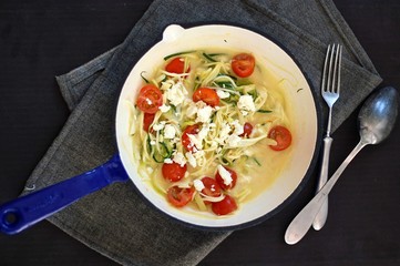 Creamy zucchini spaghetti in sauce with tomato and cheese