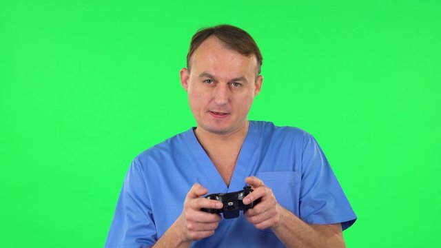 Medical man playing a video game using a wireless controller and loses. Green screen