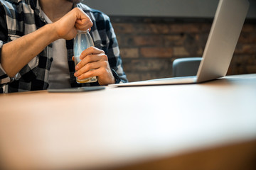 Male hands holding bottle with water indoors