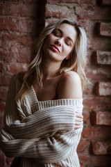Fototapeta premium Beautiful blonde woman in a silk red dress combination posing over loft background. Fashion beauty portrait
