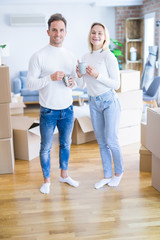 Obraz premium Young beautiful couple standing drinking cup of coffee at new home around cardboard boxes
