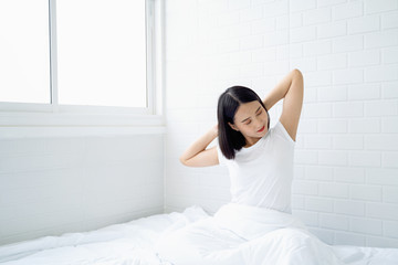 Fototapeta na wymiar Beautiful Asian woman waking up on her bed in the bedroom, she is stretching and smiling after wake up, Asia women exercising in the morning, feels refreshed.good dream last night, lifestyle in home