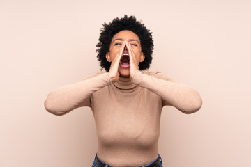 African american woman over isolated background shouting and announcing something