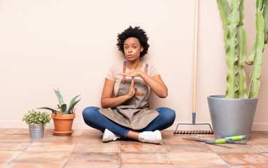 Gardener woman sitting on the floor making time out gesture