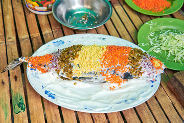Fried tuna fish covered with onions, carrots and cheese presented on a plate decorated with slices of cucumber. It is a native dish in the Philippines