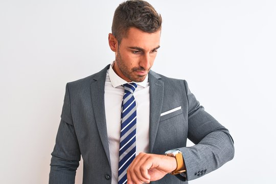 Young handsome business man wearing suit and tie over isolated background Checking the time on wrist watch, relaxed and confident