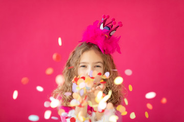 Fototapeta na wymiar Fancy girl blowing confetti against pink bakground