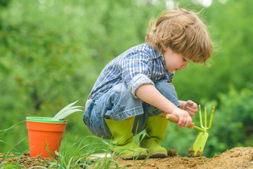 Organic farming. The child works with the ground. The game of the farmer. The boy in the garden. - 316389837