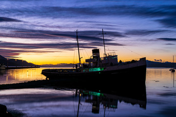 Fototapeta premium Saint Christopher boat silhouette on a colorful sunrise in Ushuaia, Tierra del Fuego, Argentina