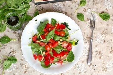 Vegetable salad with spinach,tomato,pepper,chickpea and greeen pesto on white plate