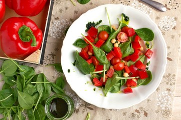 Vegetable salad with spinach,tomato,pepper,chickpea and greeen pesto on white plate