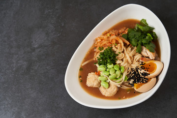 Asian noodles soup, ramen with chicken, tofu, vegetables and egg, close-up