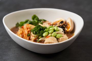 Asian noodles soup, ramen with chicken, tofu, vegetables and egg, close-up