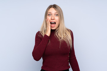Young blonde woman over isolated blue background with surprise and shocked facial expression
