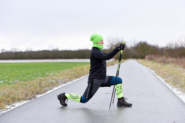 Happy woman tourist trains nordic walking in the cold morning. Healthy concept.