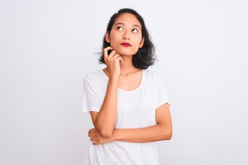 Young chinese woman wearing casual t-shirt standing over isolated white background with hand on chin thinking about question, pensive expression. Smiling with thoughtful face. Doubt concept.