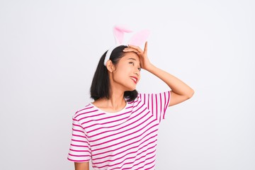Young beautiful chinese woman wearing banny ears standing over isolated white background stressed with hand on head, shocked with shame and surprise face, angry and frustrated. Fear and upset