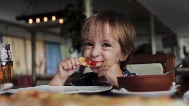 Close up of little cute boy eating pizza. Neutral colors for collor correction.