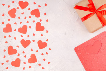 Valentine's Background with Gift Box with Red Ribbon Bow, Valentine Card and Confetti Paper Hearts on Concrete Gray Background. Love, Romance, Happy Valentines Day Concept. Top View