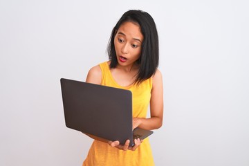 Young beautiful chinese woman using laptop standing over isolated white background scared in shock with a surprise face, afraid and excited with fear expression