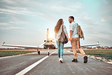 Young couple walking on runway. People carring backpacks