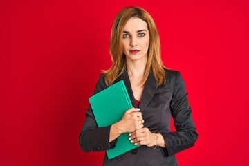Fototapeta premium Young beautiful redhead businesswoman wearing suit holding book