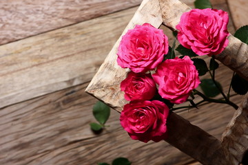 festive background with roses in a frame on a wooden table