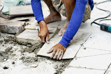 construction worker installing ceramic tiles on a floor . Tiling Floor                                 