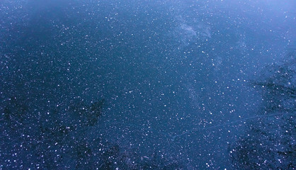 Snowflakes on the dark ice. The background image resembling a dark starry sky