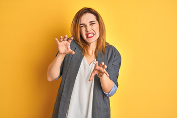 Redhead caucasian business woman over yellow isolated background smiling funny doing claw gesture as cat, aggressive and sexy expression