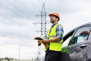 A man in a helmet and uniform, an electrician in the field. Professional electrician engineer...