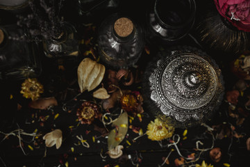 vintage jars, bottles, containers, flowers in smoke and dry leaves on a wooden table with warm light