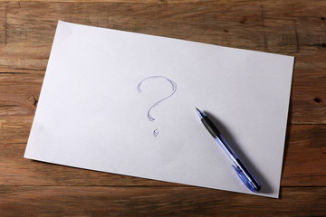 a piece of paper with a question mark on a wooden table