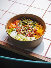 Poke bowl with tuna and vegetables on the white tile table