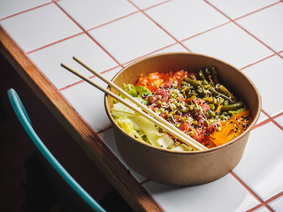 Poke bowl with tuna and vegetables on the white tile table