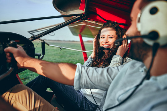 Happy young couple sitting in cabine of small airplane
