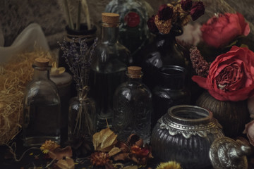 vintage jars, bottles, containers, flowers in smoke and dry leaves on a wooden table with warm light