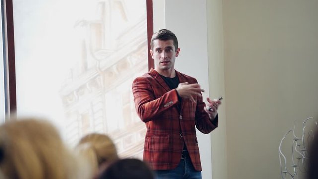 Man speaker teaching public in the hall. Professional expert talking to audience looking at the presentation.