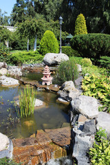 Fototapeta na wymiar Beautiful artificial water cascade. Asian-style pond. Little pagoda. Garden decoration