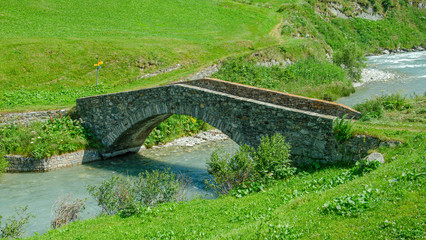 Fototapeta na wymiar Steinbrücke über Fluss in Landschaft