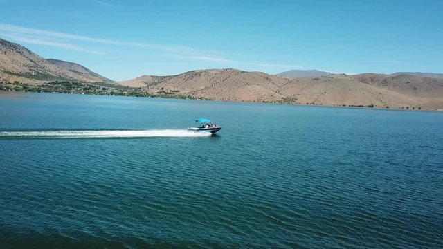 Dramatic Aerial View on Speedboat Sailing on Surface of Topaz Lake With Overview on Arid Desert Coast  in Nevada California Border USA
