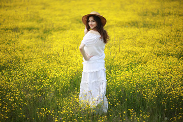 Pregnant woman in a dress in a field of flowers