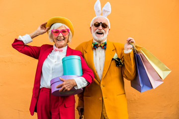 Happy elderly couple in colorful costumes posing with presents