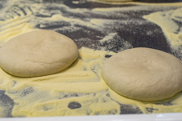 Ball of pizza dough on a rustic wooden background with dusting of flour